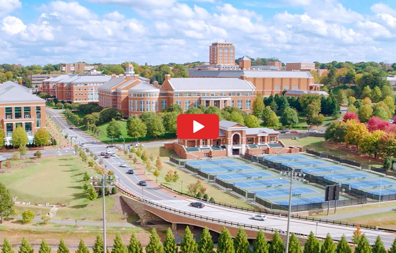 Aerial view of a university campus with brick buildings and tennis courts.