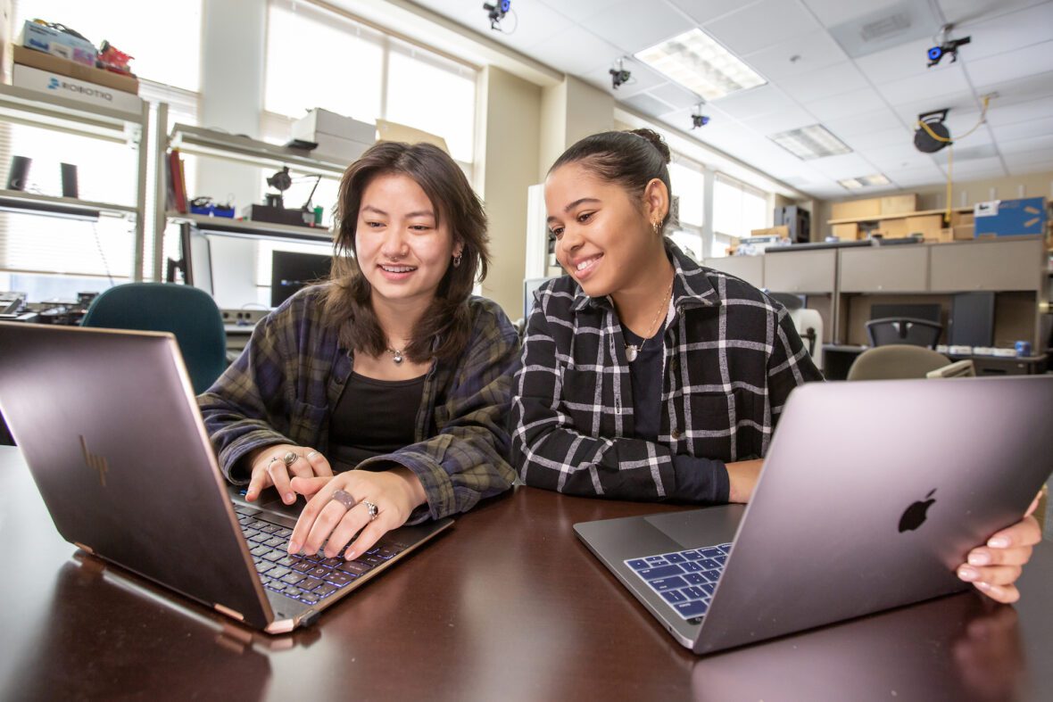 Two female UNC Charlotte College of Computing and Informatics students working on laptops